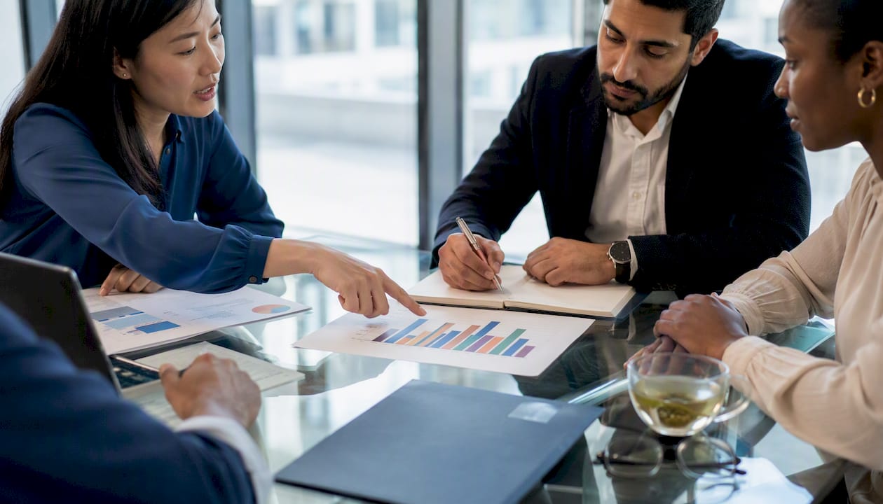 Hands analyzing financial charts on meeting table